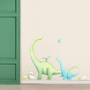 Wall decal of dinosaurs on a light beige wall with a green door.