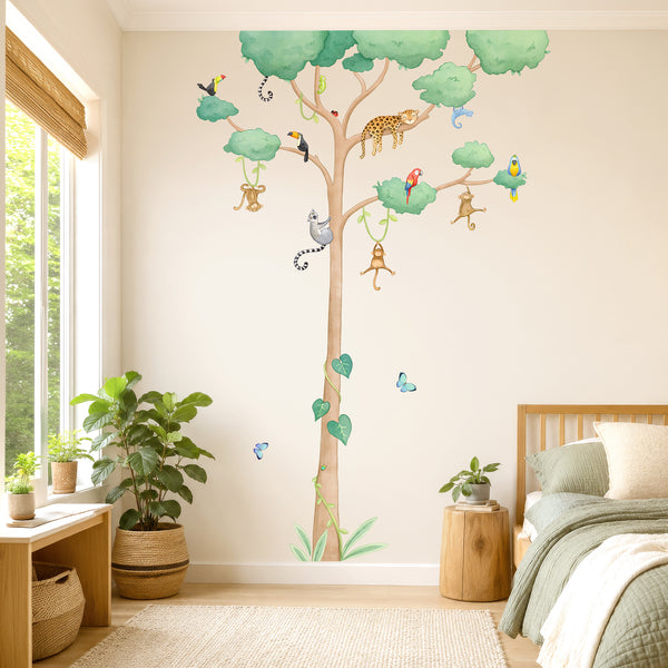 A large wall decal of a jungle tree with hanging monkeys, birds, a leopard, and colorful butterflies is displayed on a bedroom wall by a kids bed